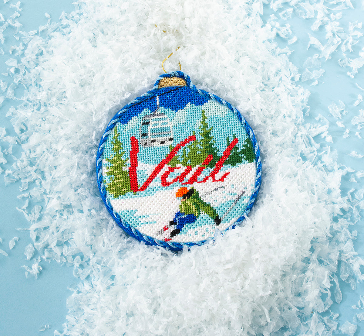 Vail finished needlepoint ornament on blue paper with fake snow