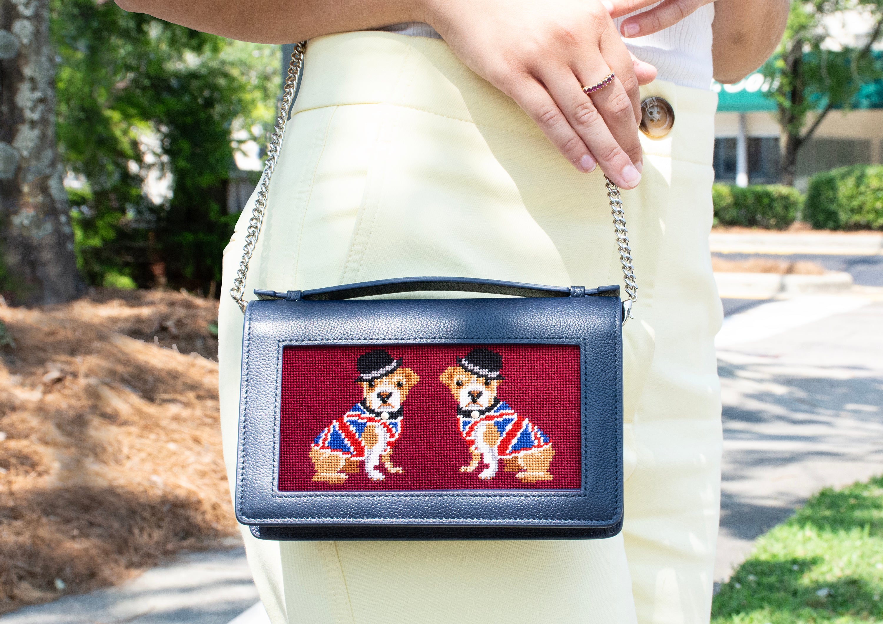 navy everyday leather clutch with red double bulldog insert against yellow pants