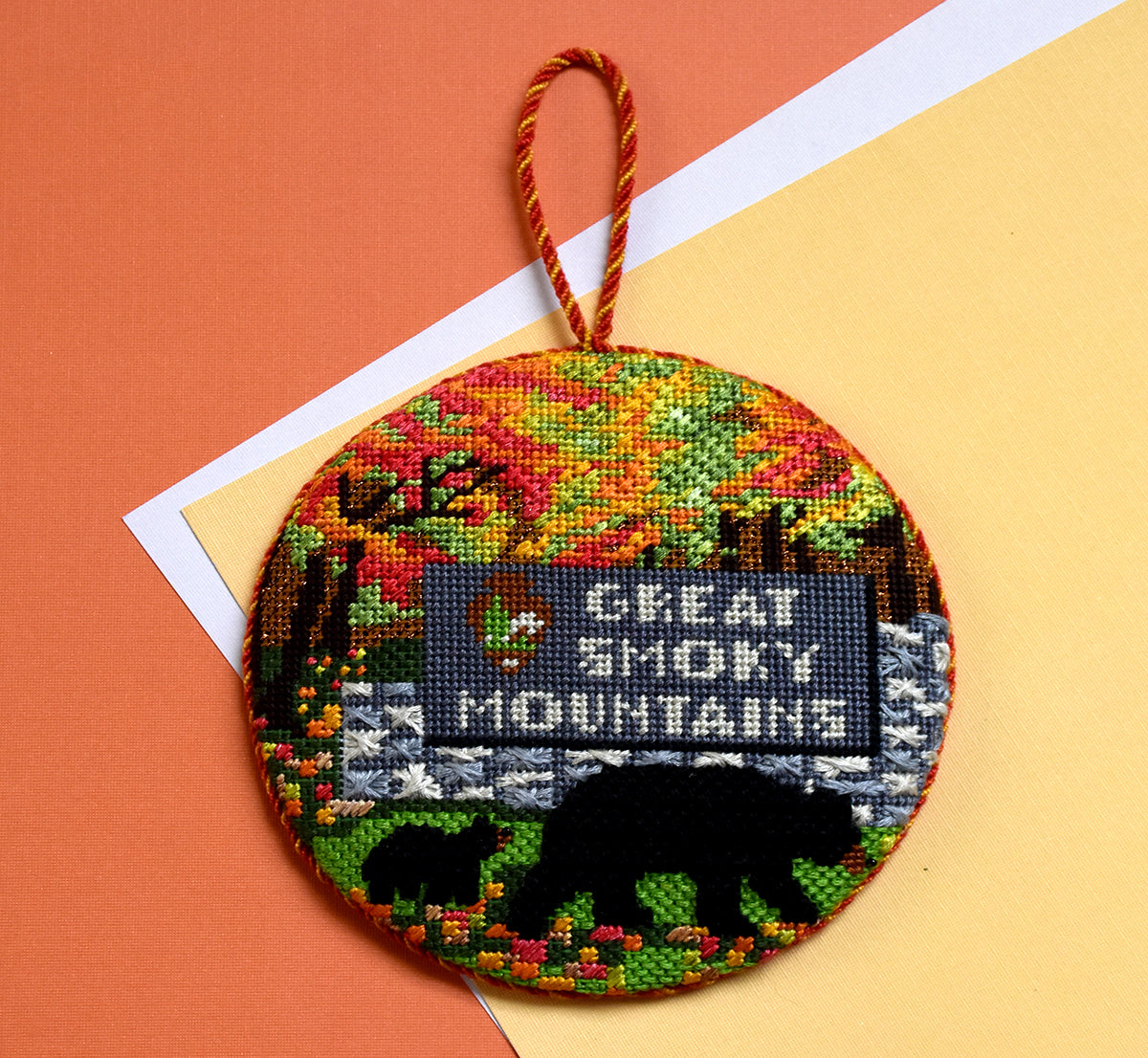 Great Smoky Mountains finished needlepoint ornament on orange paper